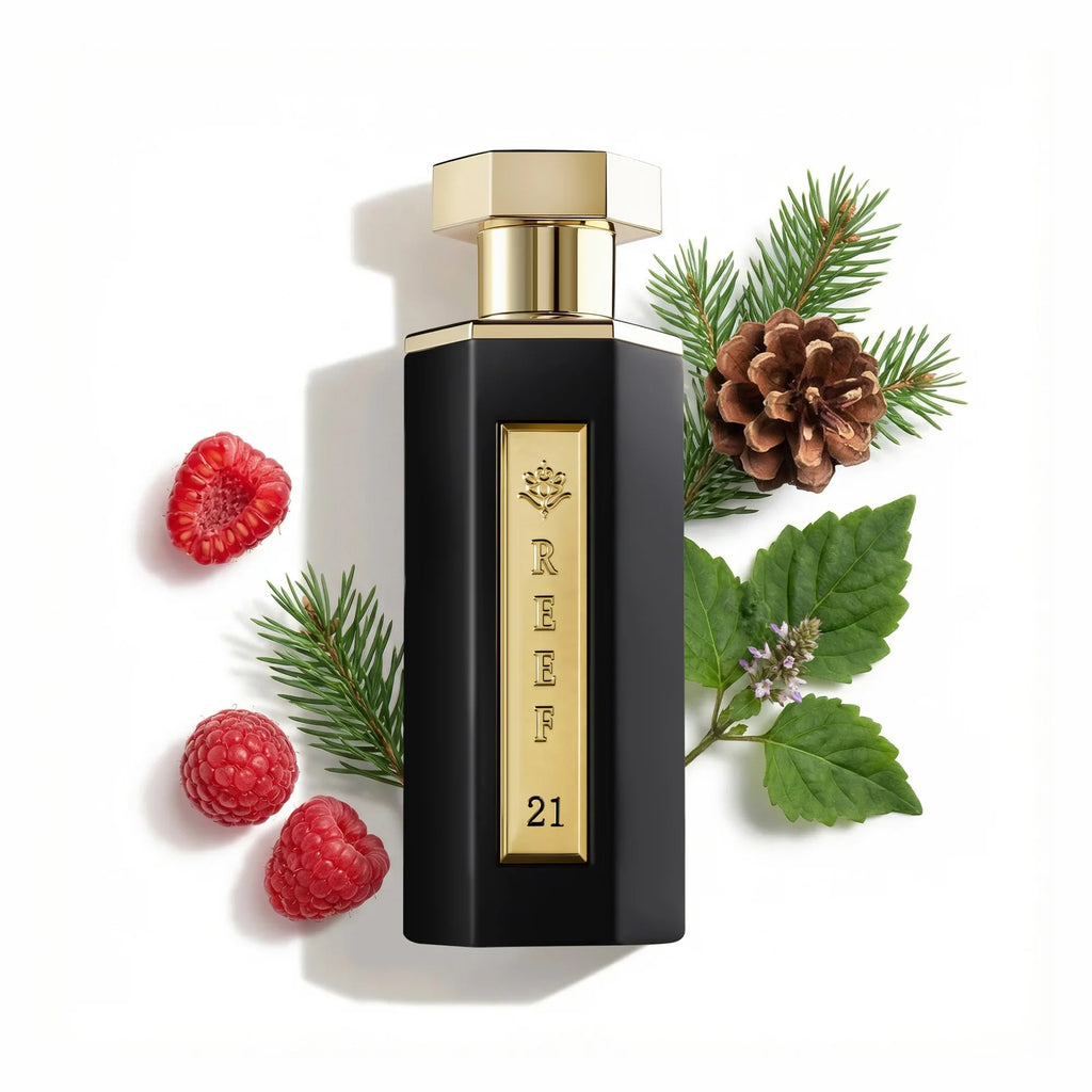 Reef - 21 Eau De Parfum 100ml bottle with gold cap and black body, surrounded by raspberries, pine cones, and leaves on a white background